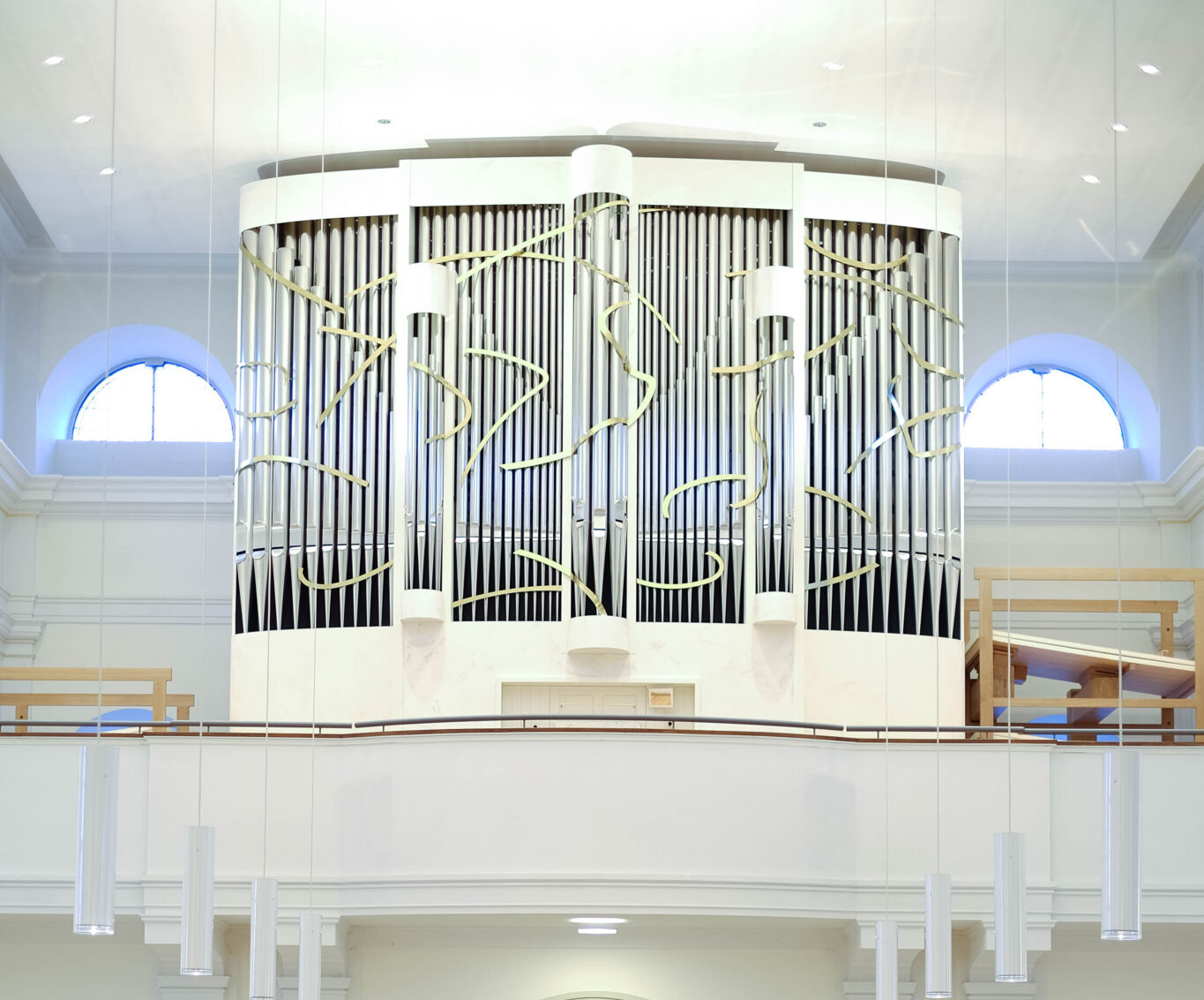 Blick auf eine Orgeltribüne im Kirchenraum mit weißer Orgel.