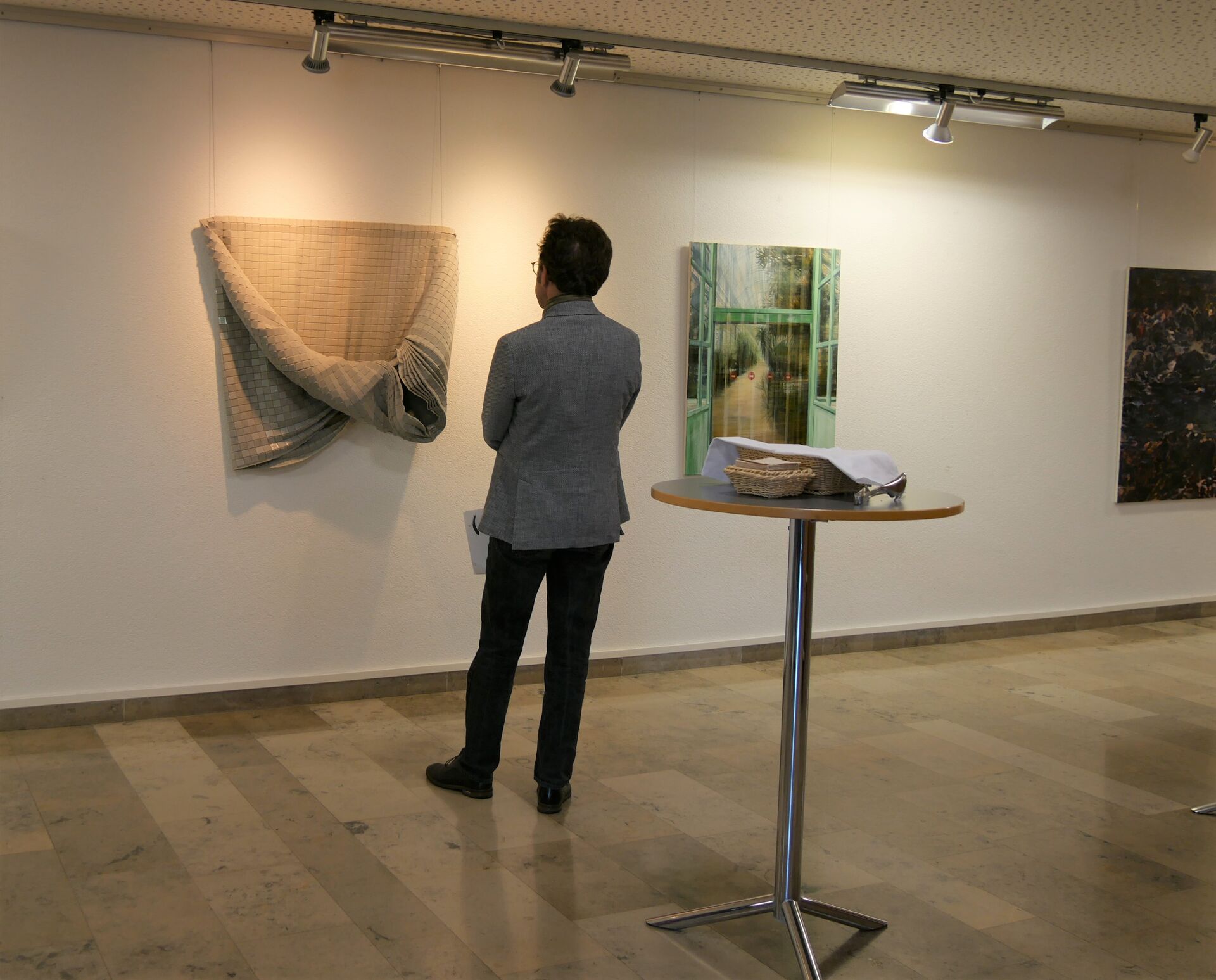 Ein Mann, Rückenansicht, betrachtet ein Kunstwerk in einem Ausstellungsraum
