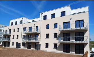 Mehrfamilienhaus weiß vor blauem Himmel