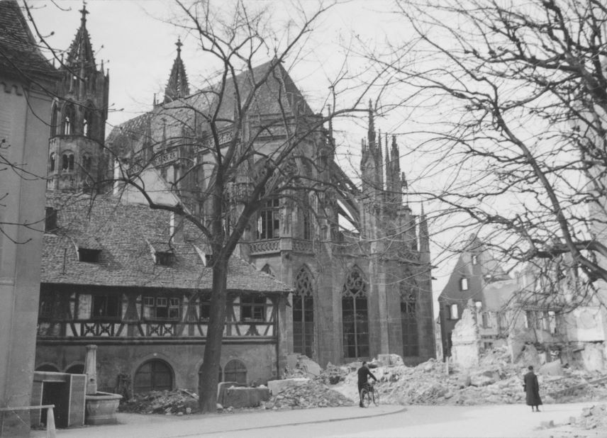 schwarz-weiß Foto, zerstörtes Haus, Schutt, davor 2 Menschen,