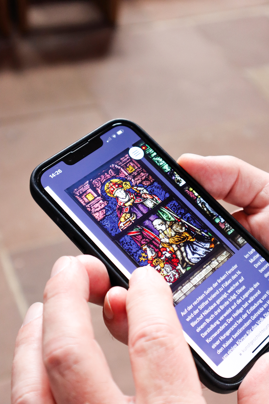 ein Handy, auf den Bildschirm ein Kirchenfenster und Text