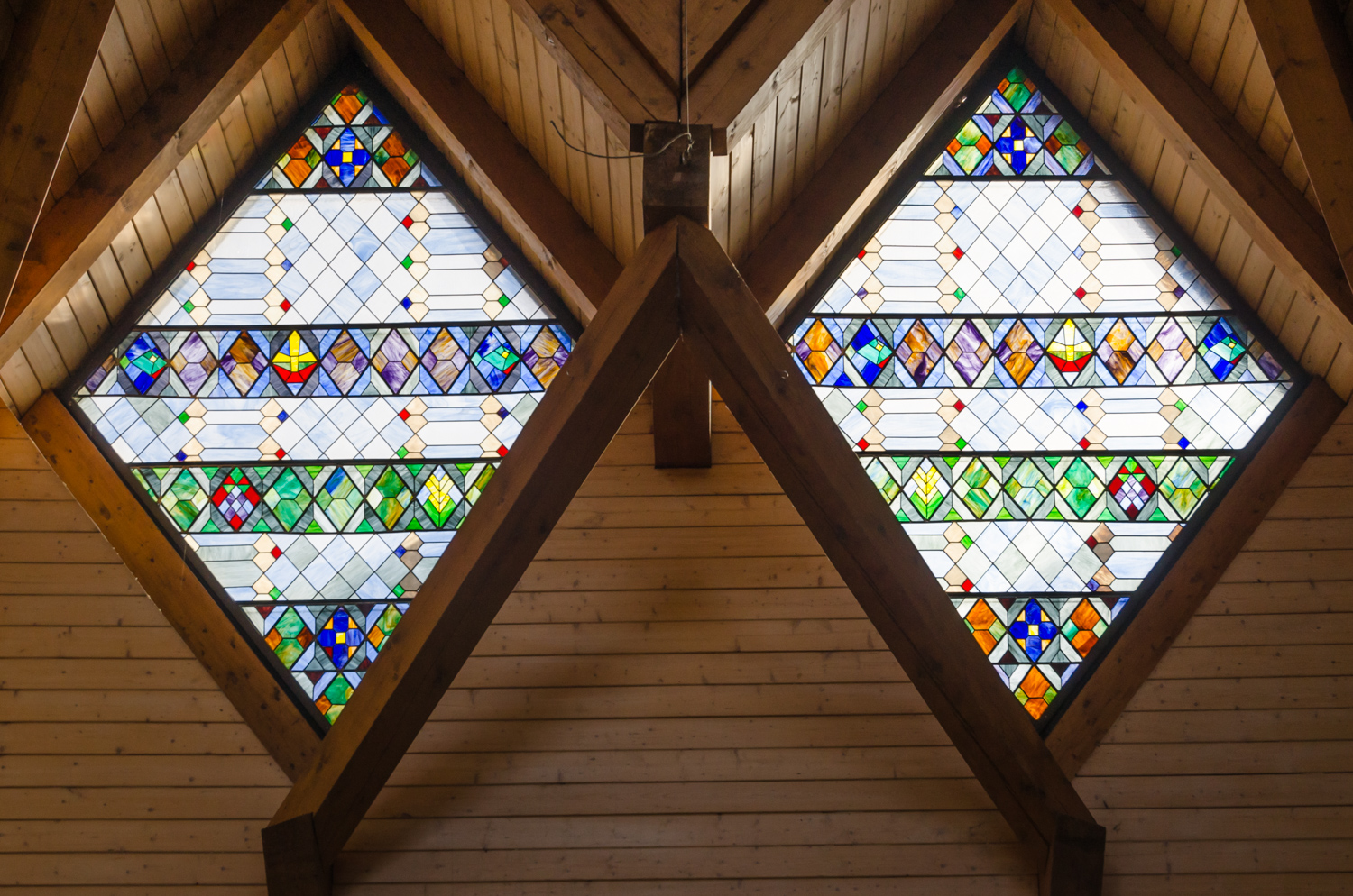 bunte Fenster aus Bleiglas in Rautenform in einer Holzdecke in einer Kirche