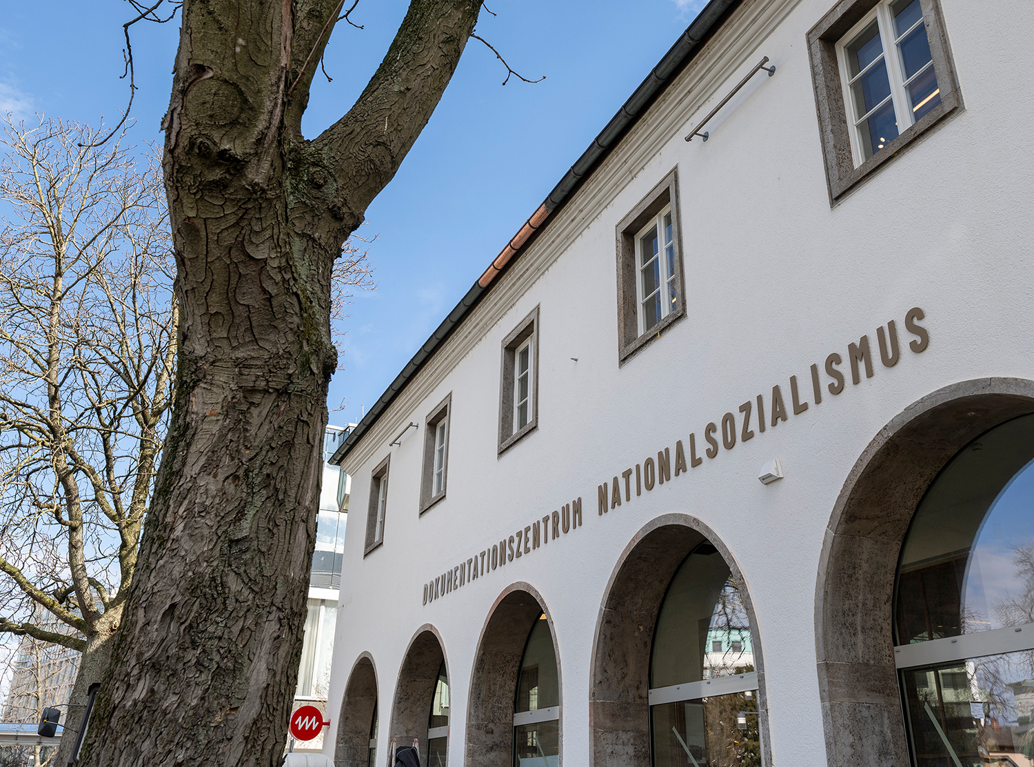 weißes Haus mit Rundbögen, darüber Beschriftung Dokumentationszentrum nationalsozialismus, vorne links ein Baum