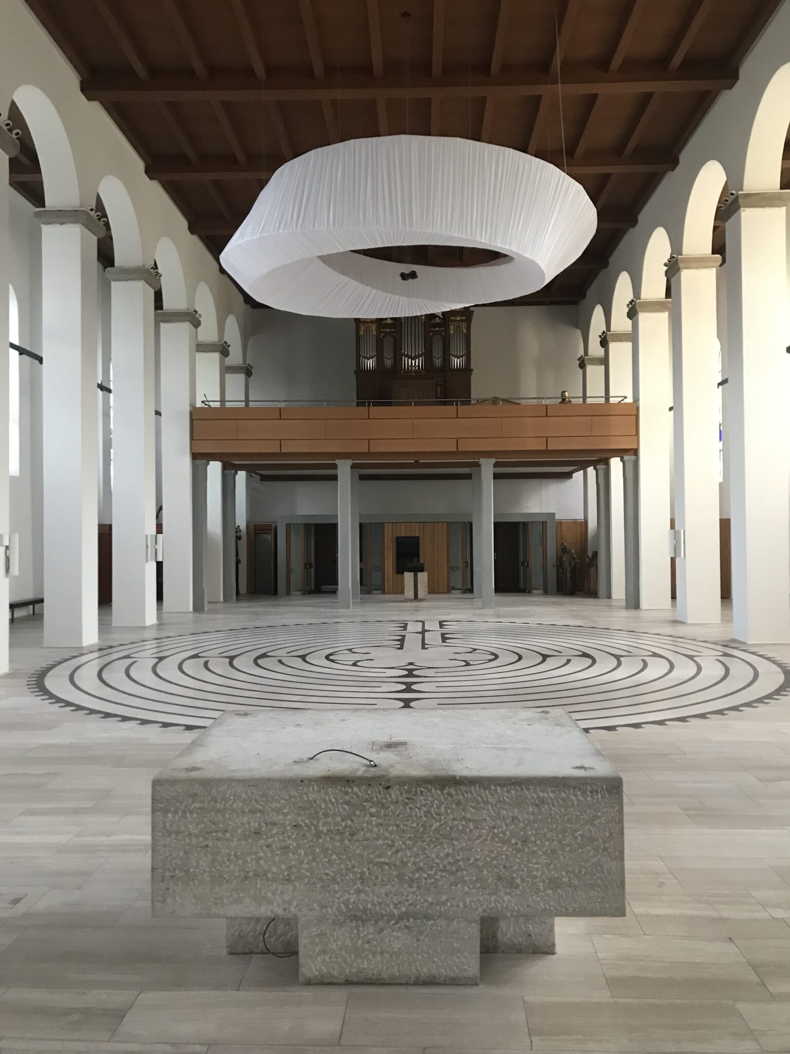 Blick in hellen Inneraum einer Kirche, auf dem Boden ein Labyrinth, vorne ein leerer Altar,