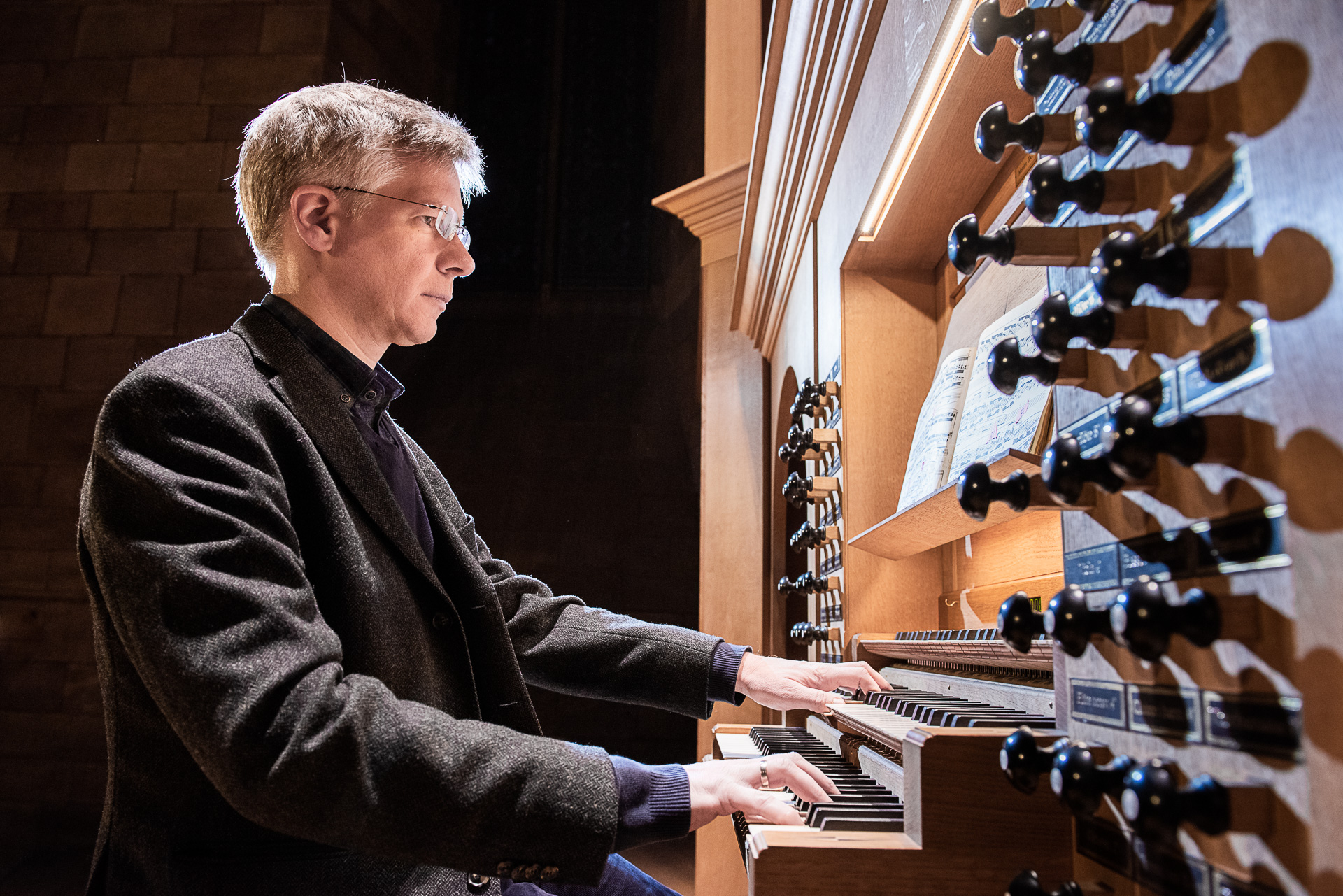 Organist spielt auf einer Orgel, von der Seite fotografiert