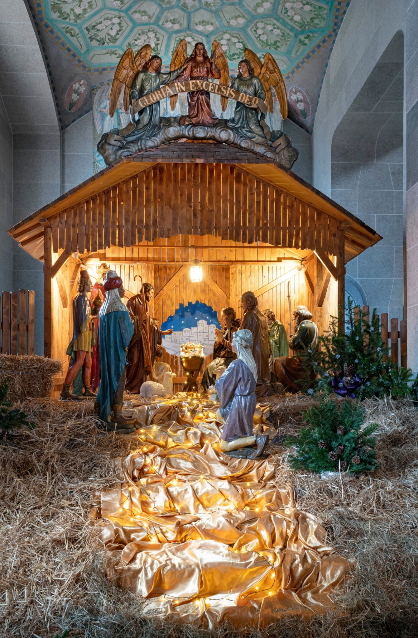 ein goldenes Tuch führt auf die Krippe zu, die Figuren stehen vor und in einem Holzstall, eine Engelgruppe steht über der Szene